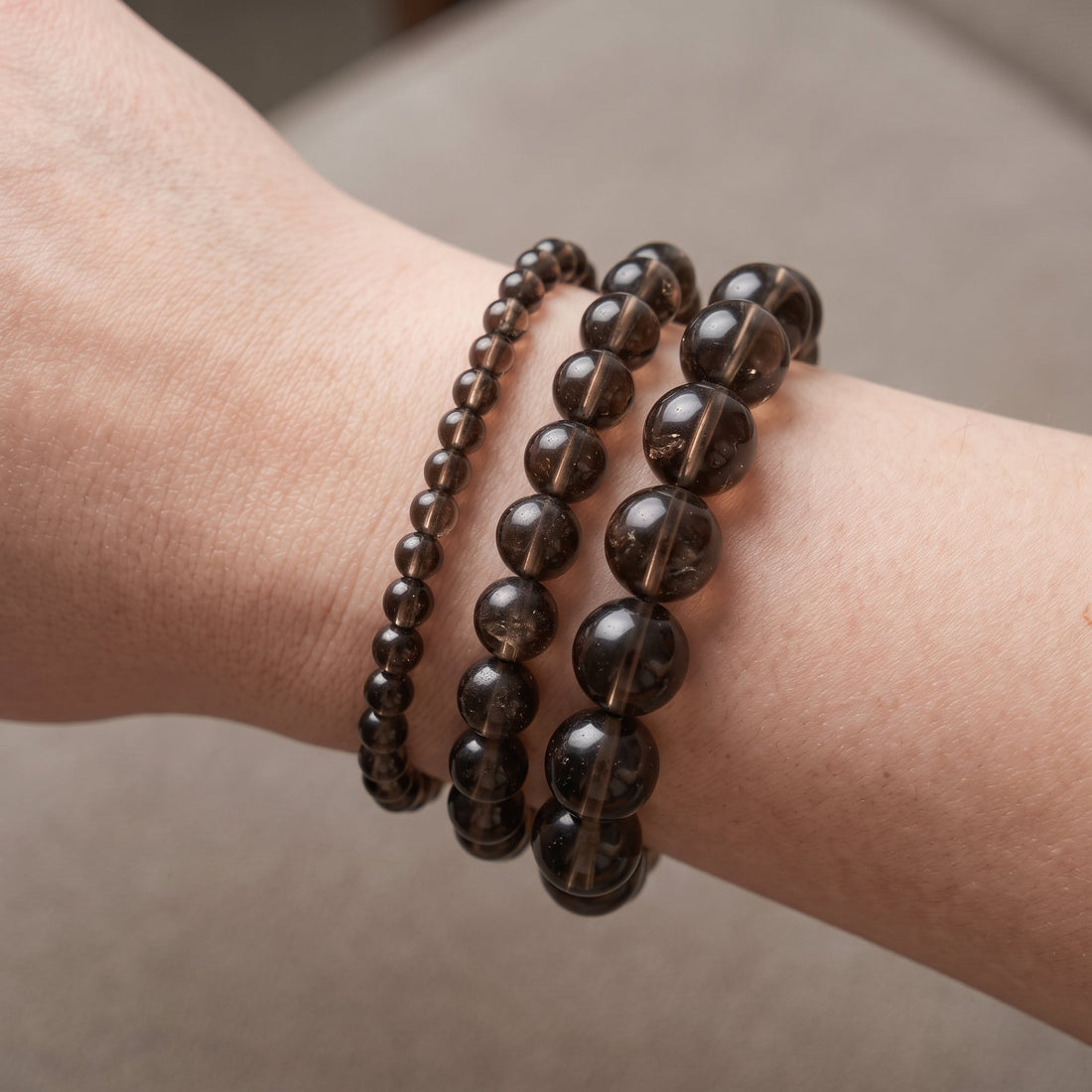 Trois bracelets en quartz fumé de diamètres différents, portés ensemble au poignet - visuel provisoire