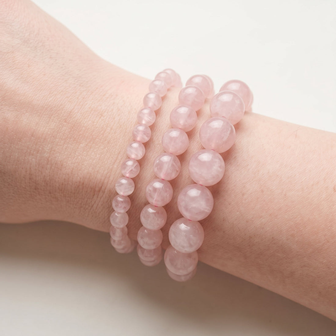 Trois bracelets en quartz rose de diamètres différents, portés ensemble au poignet - visuel provisoire