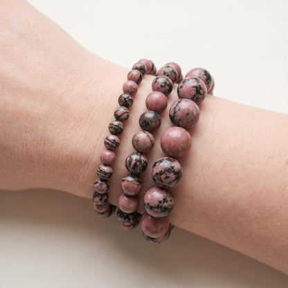 Trois bracelets en rhodonite de diamètres différents, portés ensemble au poignet - visuel provisoire