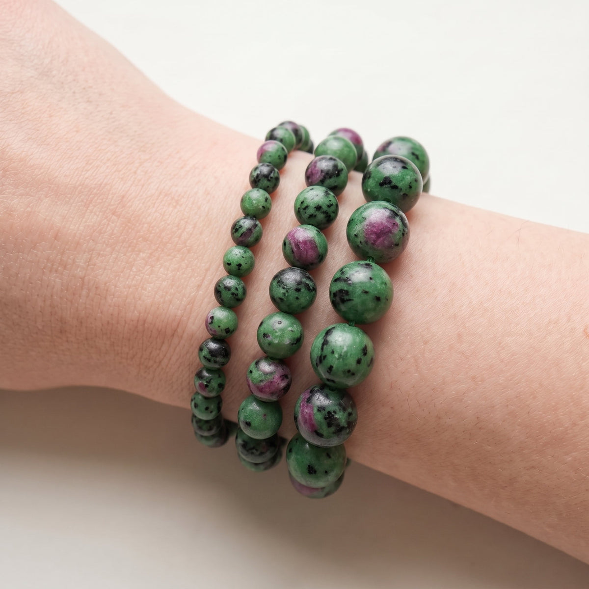 Trois bracelets en rubis zoïsite de diamètres différents, portés ensemble au poignet - visuel provisoire