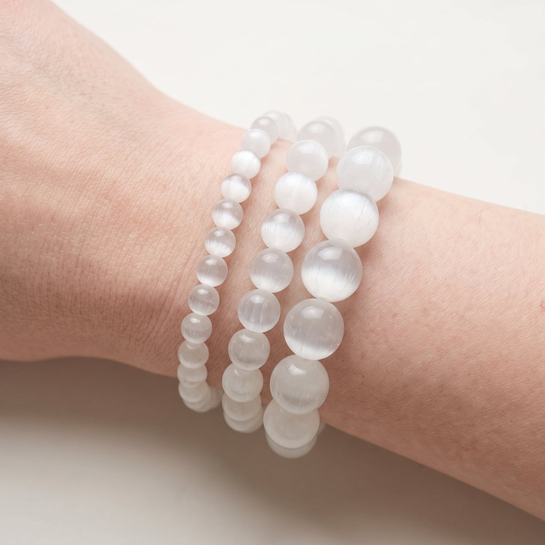 Trois bracelets en sélénite de diamètres différents, portés ensemble au poignet - visuel provisoire