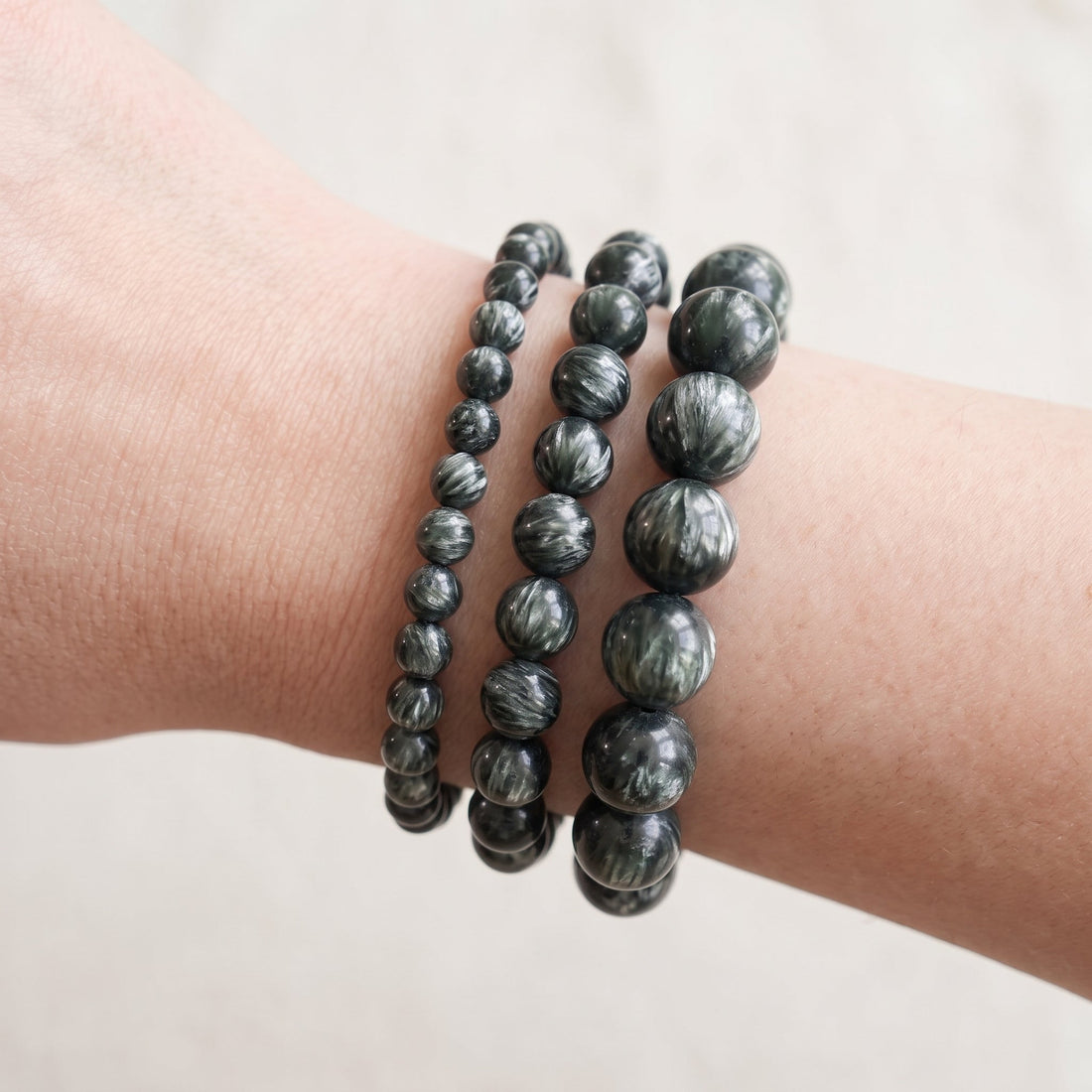 Trois bracelets en séraphinite de diamètres différents, portés ensemble au poignet - visuel provisoire
