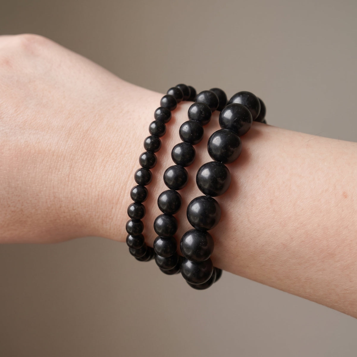Trois bracelets en tourmaline noire de diamètres différents, portés ensemble au poignet - visuel provisoire