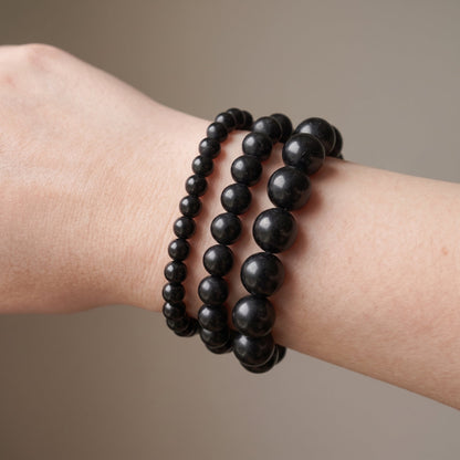 Trois bracelets en tourmaline noire de diamètres différents, portés ensemble au poignet - visuel provisoire