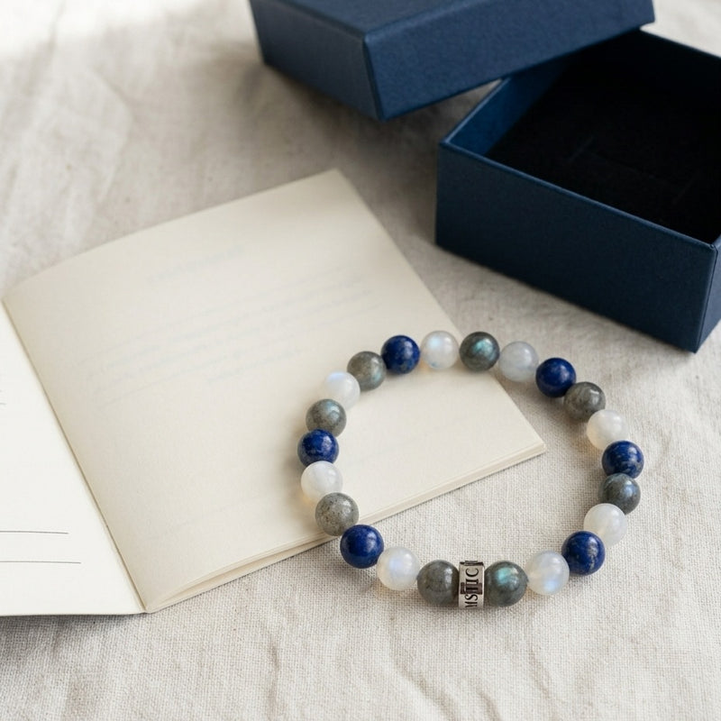 Le coffret ouvert : le bracelet, son livret et son ecrin bleu nuit, poses sur du lin ivoire - visuel provisoire