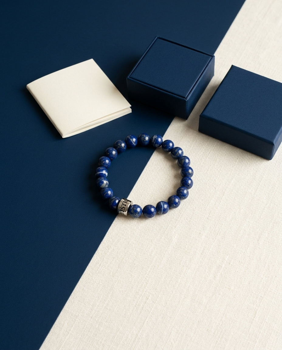 Coffret Mystic Moon : bracelet en perles de pierre naturelle avec sa perle gravée en acier, livret et boîte bleu nuit, posés sur du lin ivoire — visuel provisoire