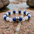 Bracelet La Boussole en lapis-lazuli, cristal de roche et pierre de lune blanche, pose sur du granit traverse d&