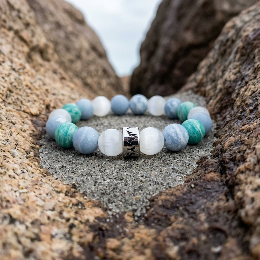 Bracelet Le Refuge en angelite, amazonite et selenite, pose sur du sable gris dans un creux de granit abrite - visuel provisoire