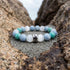 Bracelet Le Refuge en angelite, amazonite et selenite, pose sur du sable gris dans un creux de granit abrite - visuel provisoire