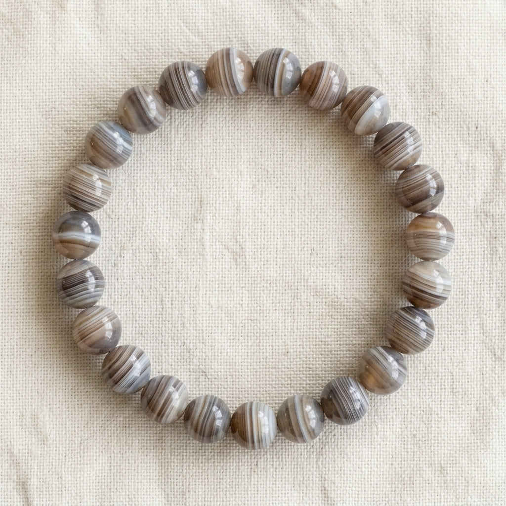 Bracelet en agate botswana : perles rondes de pierre naturelle de 8 mm sur elastique, sans interperle (variante temporaire), vu de dessus sur du lin ivoire - visuel provisoire