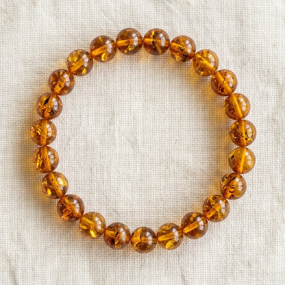 Bracelet en ambre : perles rondes de pierre naturelle de 8 mm sur elastique, sans interperle (variante temporaire), vu de dessus sur du lin ivoire - visuel provisoire