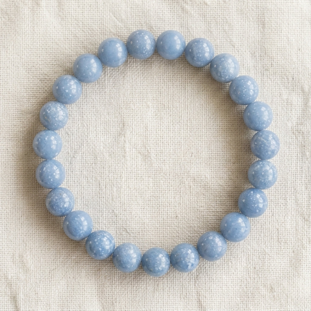 Bracelet en angélite : perles rondes de pierre naturelle de 8 mm sur elastique, sans interperle (variante temporaire), vu de dessus sur du lin ivoire - visuel provisoire