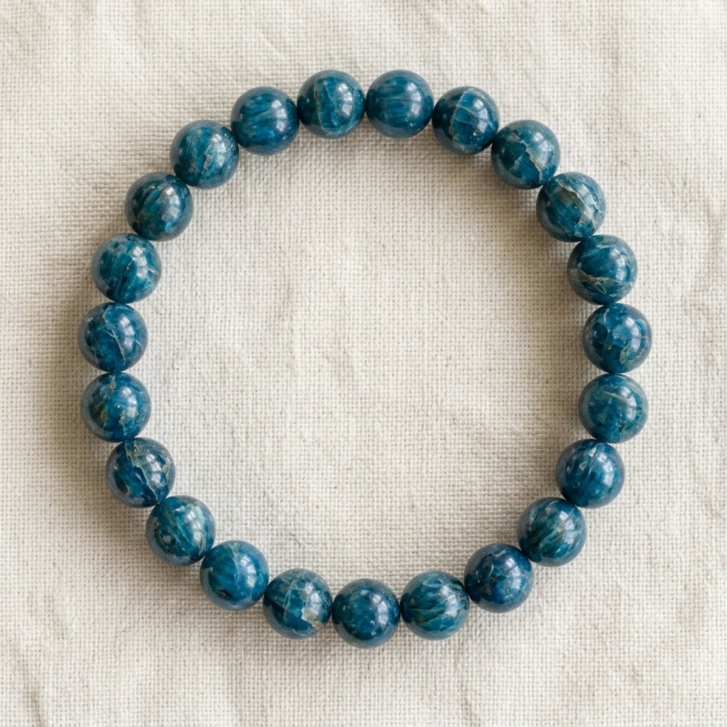 Bracelet en apatite bleue : perles rondes de pierre naturelle de 8 mm sur elastique, sans interperle (variante temporaire), vu de dessus sur du lin ivoire - visuel provisoire