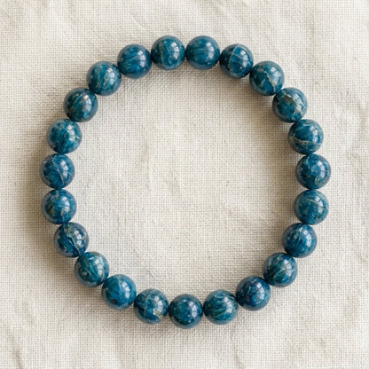 Bracelet en apatite bleue : perles rondes de pierre naturelle de 8 mm sur elastique, sans interperle (variante temporaire), vu de dessus sur du lin ivoire - visuel provisoire