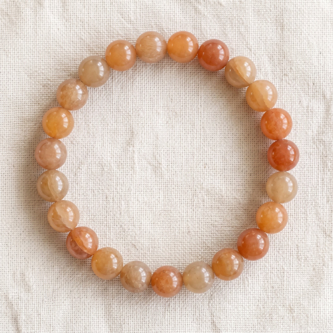 Bracelet en aventurine orange : perles rondes de pierre naturelle de 8 mm sur elastique, sans interperle (variante temporaire), vu de dessus sur du lin ivoire - visuel provisoire