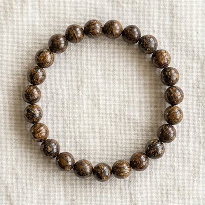 Bracelet en bronzite : perles rondes de pierre naturelle de 8 mm sur elastique, sans interperle (variante temporaire), vu de dessus sur du lin ivoire - visuel provisoire