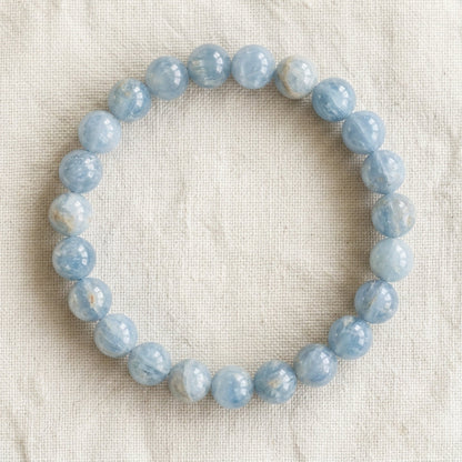 Bracelet en célestine : perles rondes de pierre naturelle de 8 mm sur elastique, sans interperle (variante temporaire), vu de dessus sur du lin ivoire - visuel provisoire