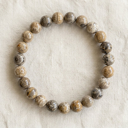 Bracelet en corail fossilisé : perles rondes de pierre naturelle de 8 mm sur elastique, sans interperle (variante temporaire), vu de dessus sur du lin ivoire - visuel provisoire