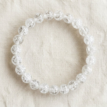 Bracelet en cristal de roche : perles rondes de pierre naturelle de 8 mm sur elastique, sans interperle (variante temporaire), vu de dessus sur du lin ivoire - visuel provisoire