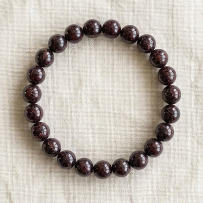 Bracelet en grenat : perles rondes de pierre naturelle de 8 mm sur elastique, sans interperle (variante temporaire), vu de dessus sur du lin ivoire - visuel provisoire