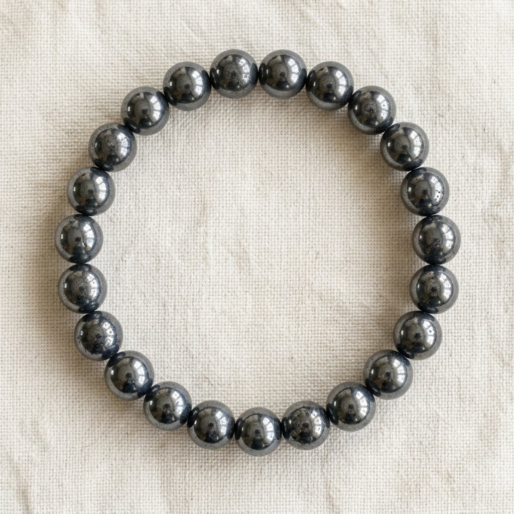 Bracelet en hematite : perles rondes de pierre naturelle de 8 mm sur elastique, sans interperle (variante temporaire), vu de dessus sur du lin ivoire - visuel provisoire