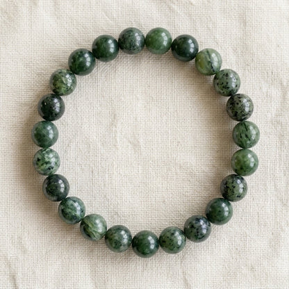 Bracelet en jade néphrite : perles rondes de pierre naturelle de 8 mm sur elastique, sans interperle (variante temporaire), vu de dessus sur du lin ivoire - visuel provisoire
