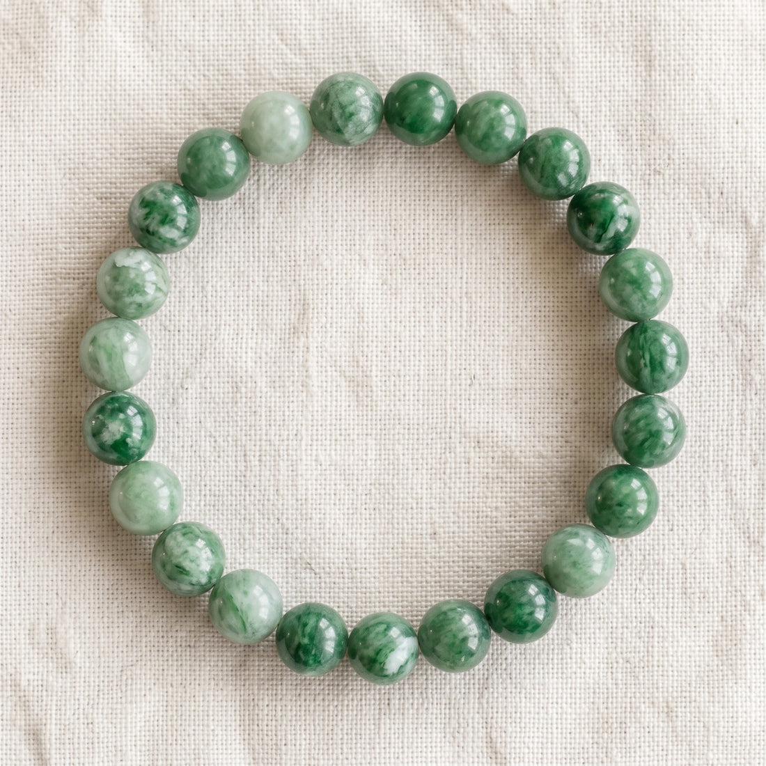 Bracelet en jade verte : perles rondes de pierre naturelle de 8 mm sur elastique, sans interperle (variante temporaire), vu de dessus sur du lin ivoire - visuel provisoire