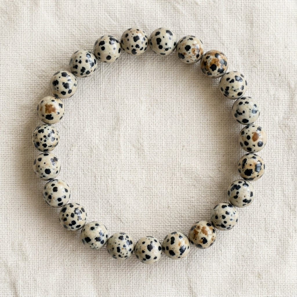 Bracelet en jaspe dalmatien : perles rondes de pierre naturelle de 8 mm sur elastique, sans interperle (variante temporaire), vu de dessus sur du lin ivoire - visuel provisoire