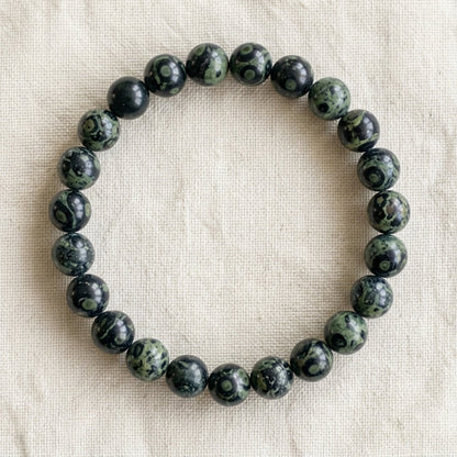Bracelet en jaspe kambaba : perles rondes de pierre naturelle de 8 mm sur elastique, sans interperle (variante temporaire), vu de dessus sur du lin ivoire - visuel provisoire