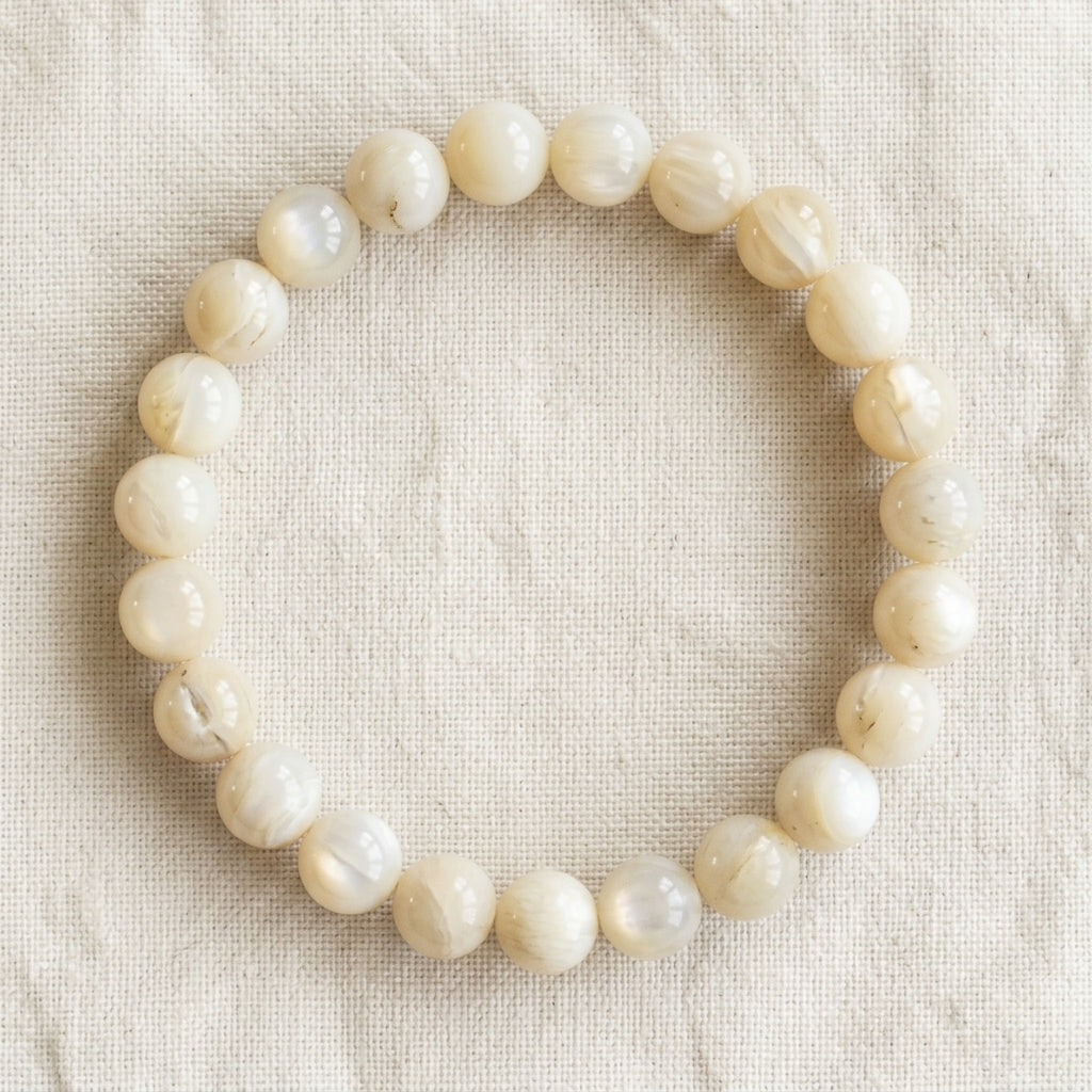Bracelet en nacre : perles rondes de pierre naturelle de 8 mm sur elastique, sans interperle (variante temporaire), vu de dessus sur du lin ivoire - visuel provisoire