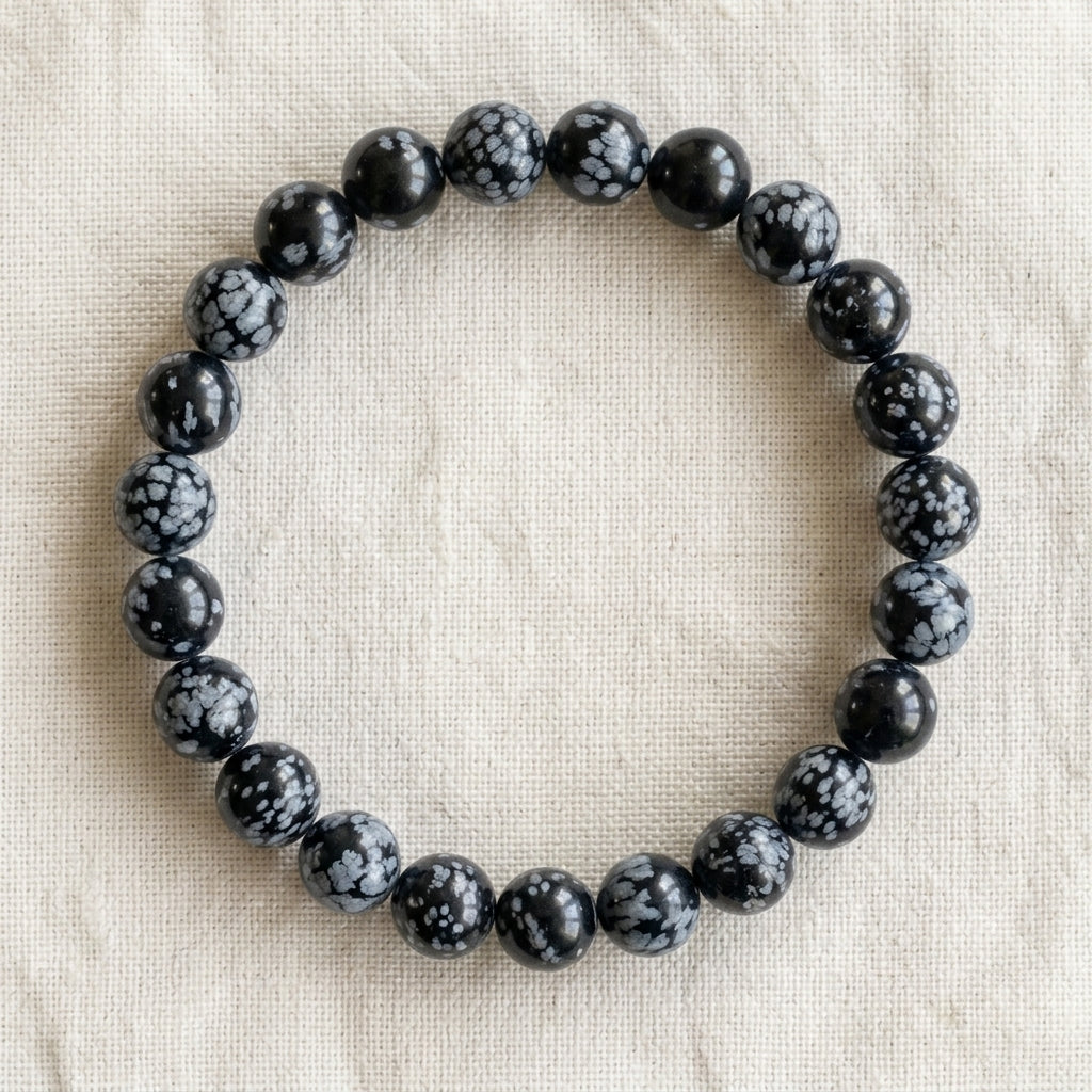 Bracelet en obsidienne neige : perles rondes de pierre naturelle de 8 mm sur elastique, sans interperle (variante temporaire), vu de dessus sur du lin ivoire - visuel provisoire