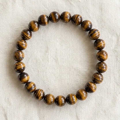 Bracelet en oeil de tigre : perles rondes de pierre naturelle de 8 mm sur elastique, sans interperle (variante temporaire), vu de dessus sur du lin ivoire - visuel provisoire