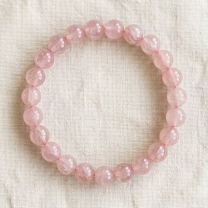 Bracelet en quartz rose : perles rondes de pierre naturelle de 8 mm sur elastique, sans interperle (variante temporaire), vu de dessus sur du lin ivoire - visuel provisoire