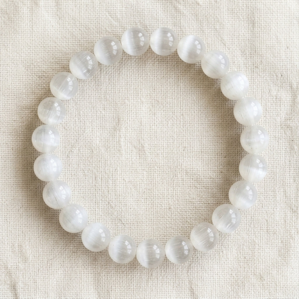 Bracelet en sélénite : perles rondes de pierre naturelle de 8 mm sur elastique, sans interperle (variante temporaire), vu de dessus sur du lin ivoire - visuel provisoire