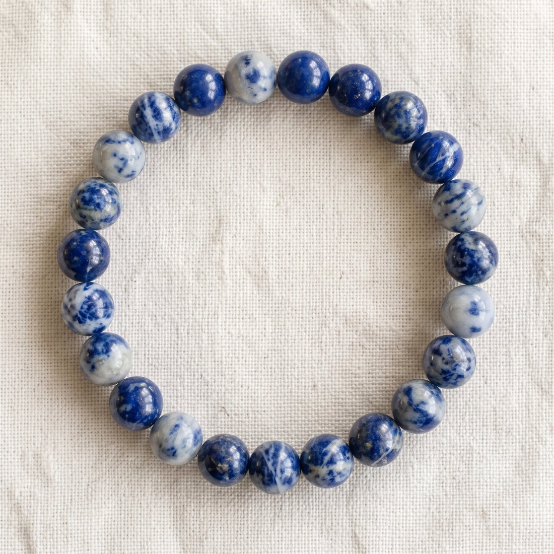 Bracelet en sodalite : perles rondes de pierre naturelle de 8 mm sur elastique, sans interperle (variante temporaire), vu de dessus sur du lin ivoire - visuel provisoire