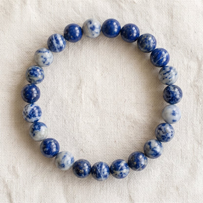 Bracelet en sodalite : perles rondes de pierre naturelle de 8 mm sur elastique, sans interperle (variante temporaire), vu de dessus sur du lin ivoire - visuel provisoire