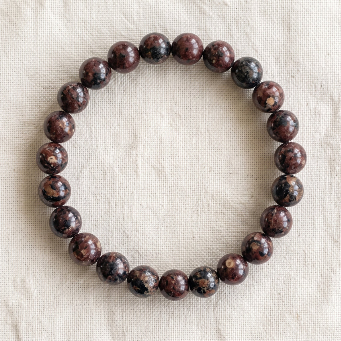 Bracelet en eudialyte : perles rondes de pierre naturelle de 8 mm sur elastique, sans interperle (variante temporaire), vu de dessus sur du lin ivoire - visuel provisoire