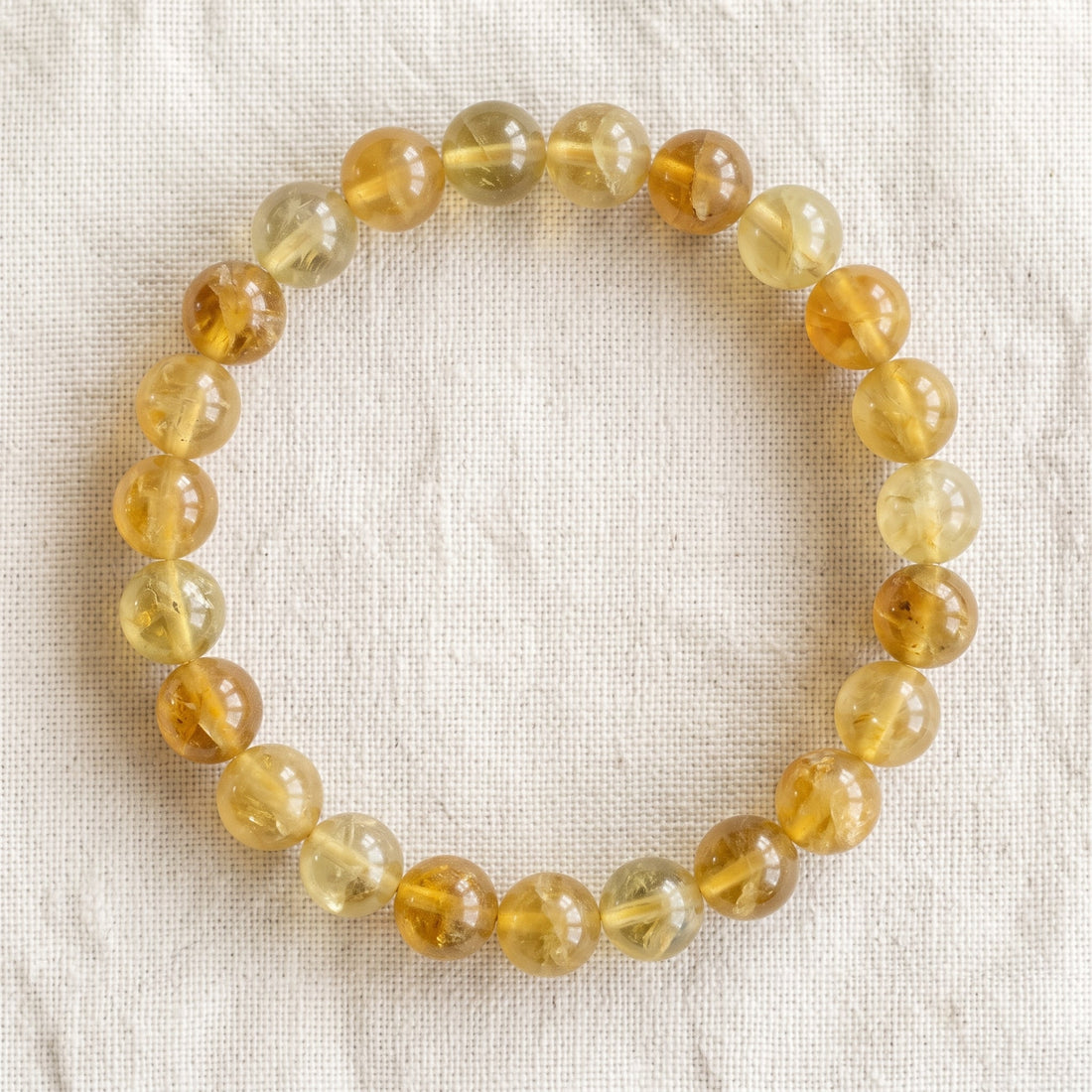 Bracelet en fluorite jaune : perles rondes de pierre naturelle de 8 mm sur elastique, sans interperle (variante temporaire), vu de dessus sur du lin ivoire - visuel provisoire