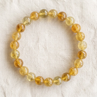 Bracelet en fluorite jaune : perles rondes de pierre naturelle de 8 mm sur elastique, sans interperle (variante temporaire), vu de dessus sur du lin ivoire - visuel provisoire
