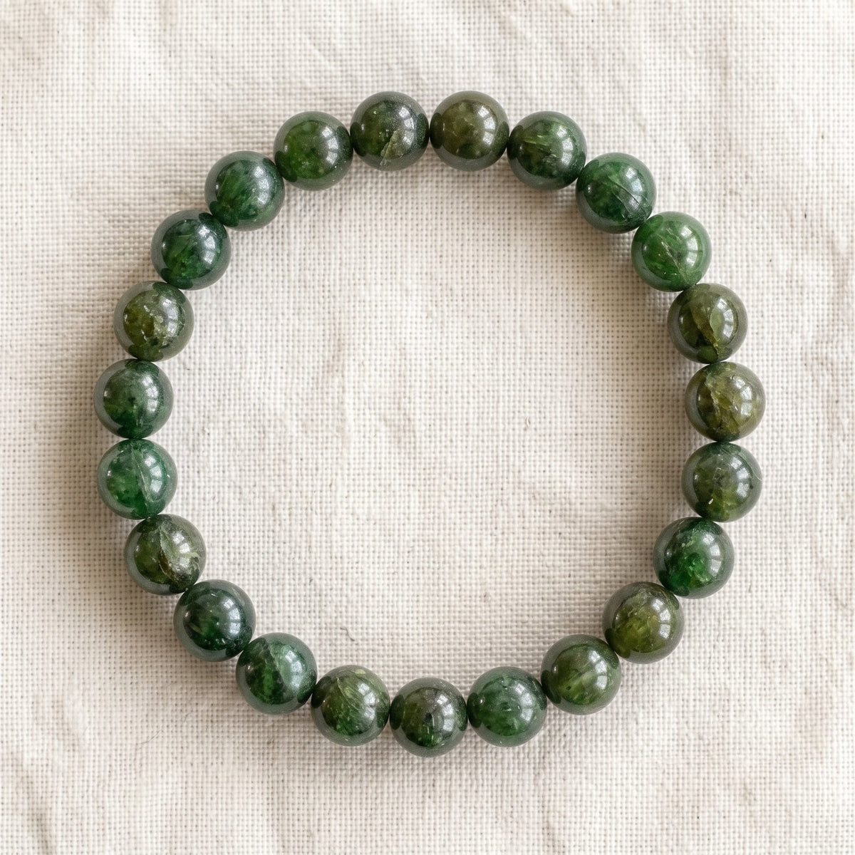 Bracelet en grenat vert : perles rondes de pierre naturelle de 8 mm sur elastique, sans interperle (variante temporaire), vu de dessus sur du lin ivoire - visuel provisoire