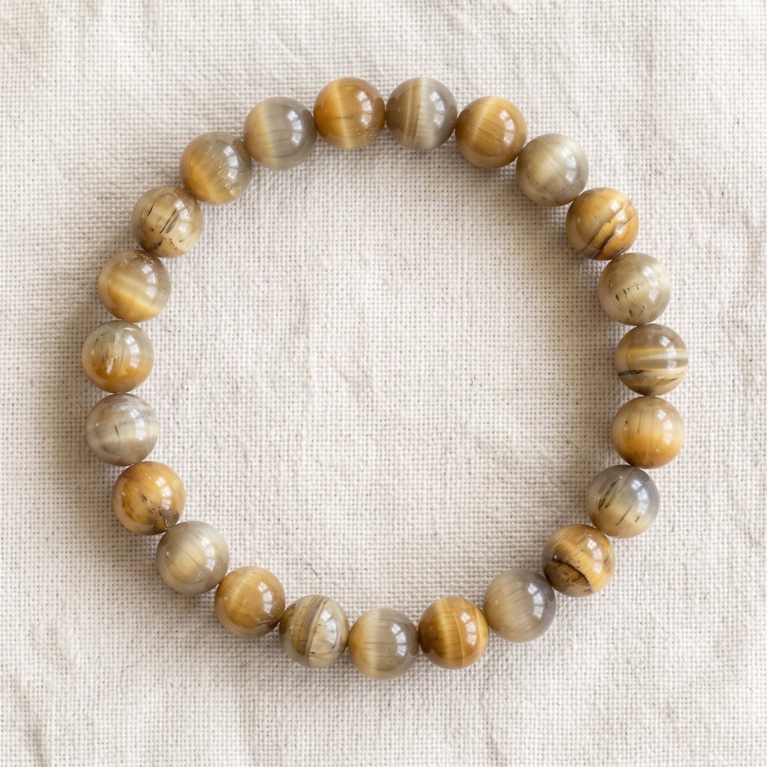 Bracelet en oeil de tigre blanc : perles rondes de pierre naturelle de 8 mm sur elastique, sans interperle (variante temporaire), vu de dessus sur du lin ivoire - visuel provisoire