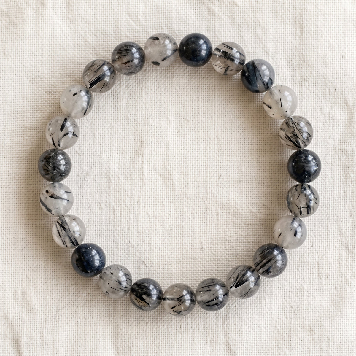 Bracelet en quartz tourmaline : perles rondes de pierre naturelle de 8 mm sur elastique, sans interperle (variante temporaire), vu de dessus sur du lin ivoire - visuel provisoire