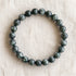 Bracelet en séraphinite : perles rondes de pierre naturelle de 8 mm sur elastique, sans interperle (variante temporaire), vu de dessus sur du lin ivoire - visuel provisoire