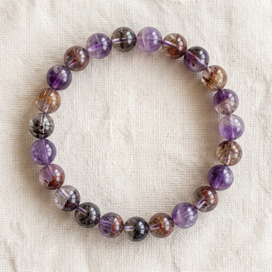 Bracelet en super seven : perles rondes de pierre naturelle de 8 mm sur elastique, sans interperle (variante temporaire), vu de dessus sur du lin ivoire - visuel provisoire
