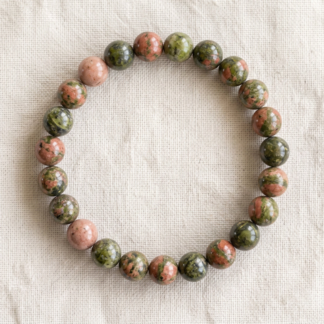 Bracelet en unakite : perles rondes de pierre naturelle de 8 mm sur elastique, sans interperle (variante temporaire), vu de dessus sur du lin ivoire - visuel provisoire
